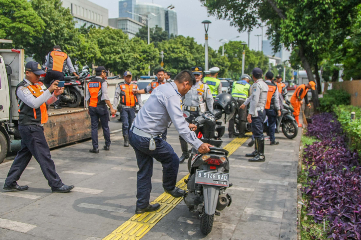 Petugas Dishub mengangkut puluhan sepeda motor yang parkir sembarangan di trotoar Jalan Salemba, Jakarta Pusat, Senin (06/04/2024). Penertib