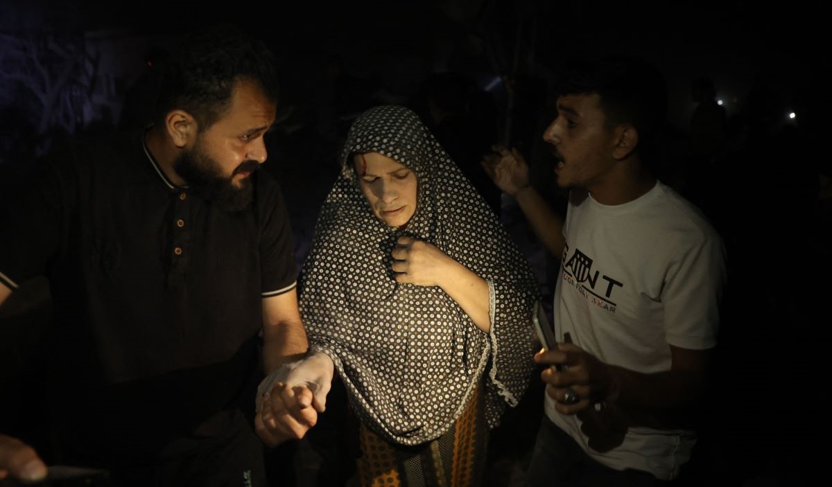 Pria Palestina membantu mengevakuasi seorang wanita dari lokasi bangunan tempat tinggal yang terkena pemboman Israel di Rafah di Jalur Gaza.