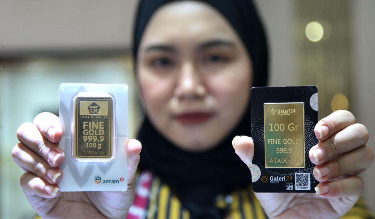 Petugas memperlihatkan emas 100 gram keluaran Antam di Pegadaian Jakarta, Selasa (6/2/2024).