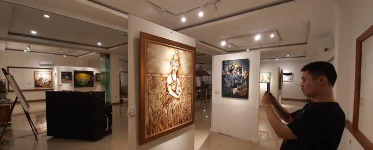 Pengunjung mengambil foto lukisan yang ditampilkan di pameran Warna-Warni Kopi di Amuya Gallery, Kemayoran, Jakarta Pusat.