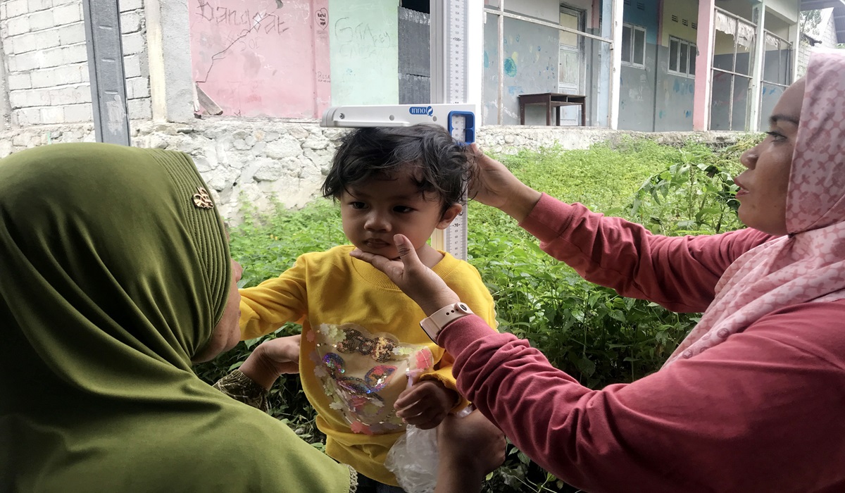 Dua kader Posyandu mengukur tinggi badan seorang anak dalam program pemeriksaan stunting di Posyandu Sedap Malam, Palu, Sulawesi Tengah.
