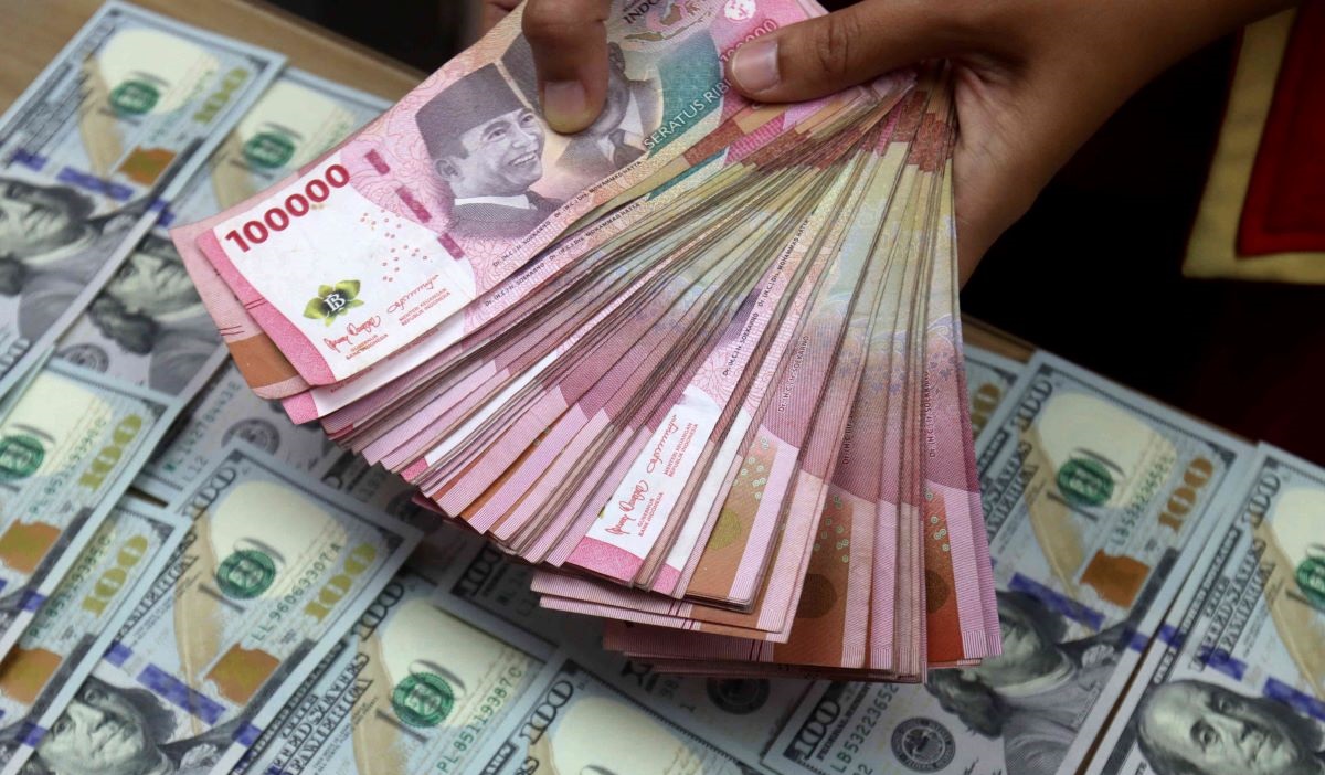 Petugas teller menunjukan uang rupiah dan dolar AS yang akan ditransaksikan, di Jakarta, Kamis (15/2/2024).