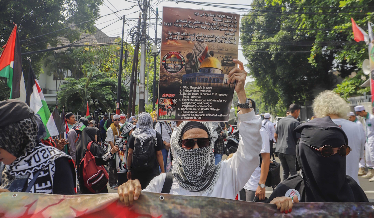 Pengunjuk rasa memegang poster Stop Genosida di Gaza saat Aksi Bela Palestina di Kantor Kedutaan Besar Mesir, Jakarta 