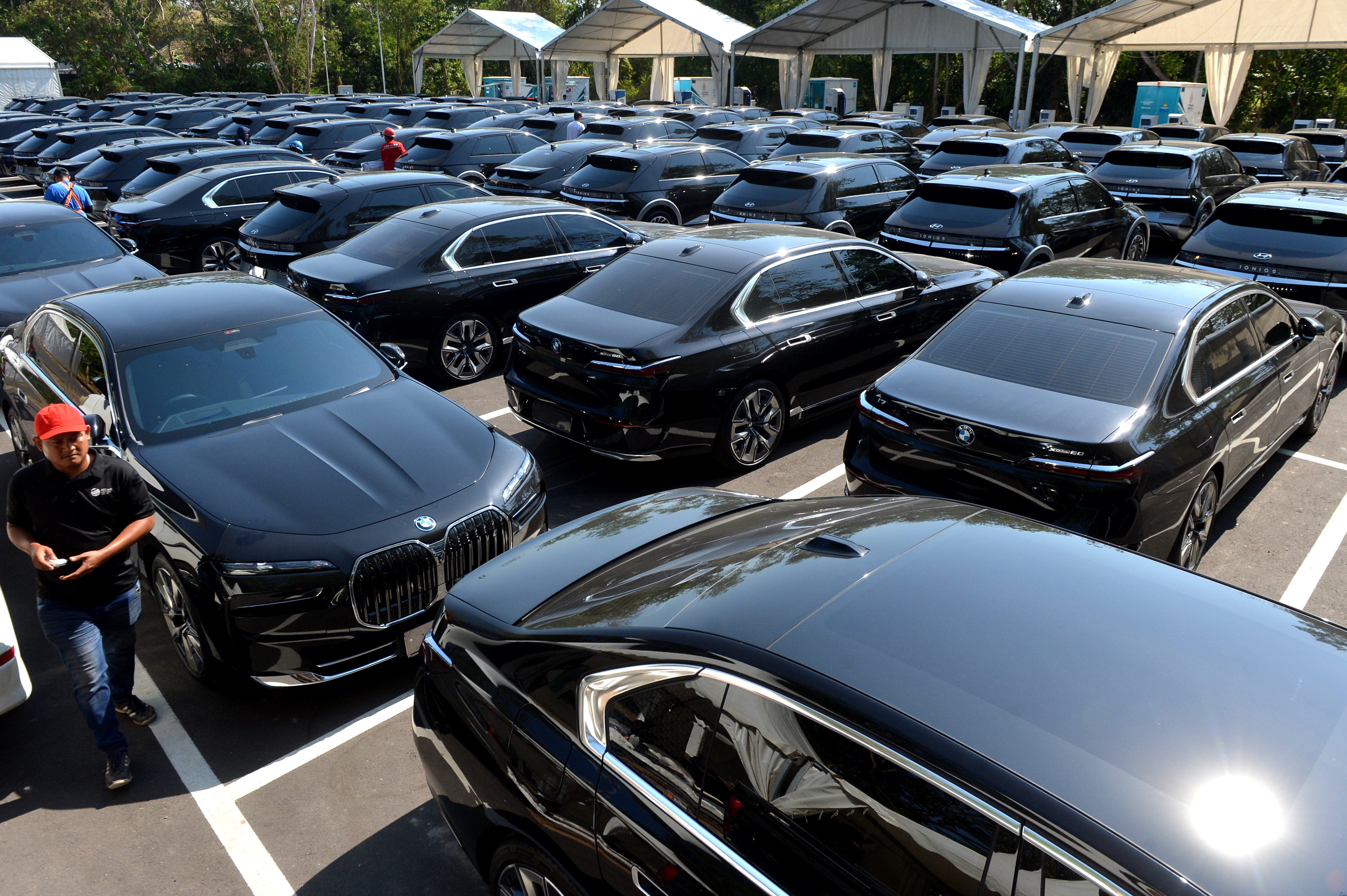 Petugas berjalan di dekat deretan mobil listrik yang terparkir