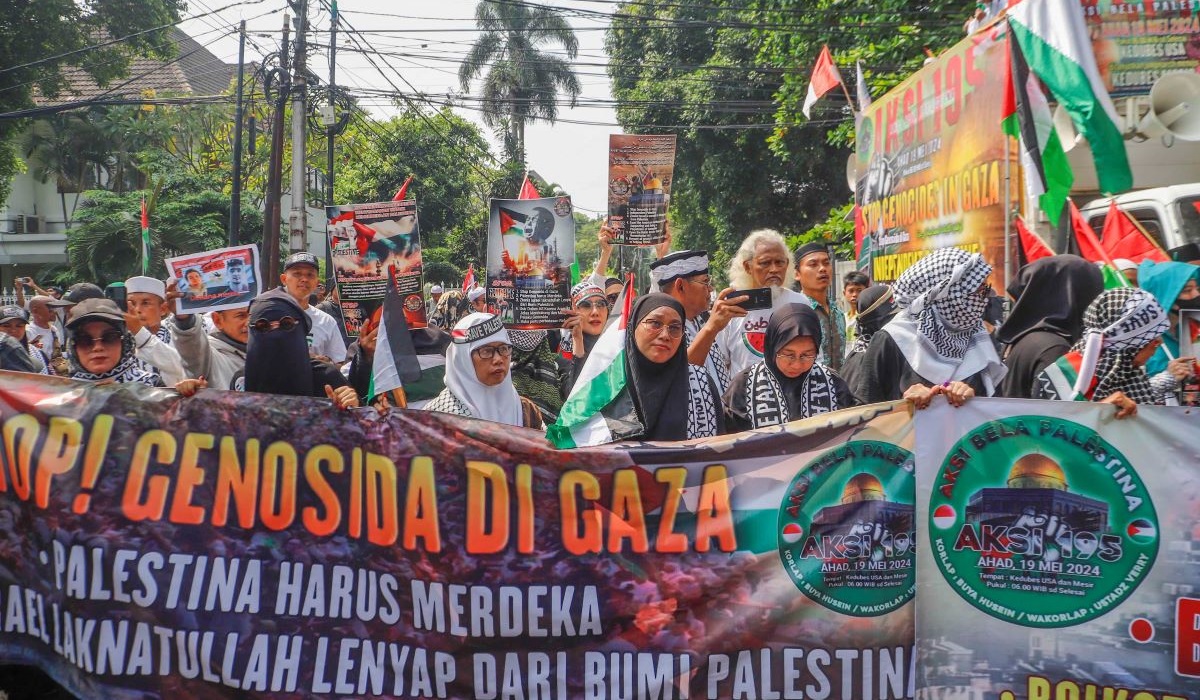 Pengunjuk rasa memegang poster Stop Genosida di Gaza saat Aksi Bela Palestina di Kantor Kedutaan Besar Mesir, Jakarta, Minggu (19/5/2024). 