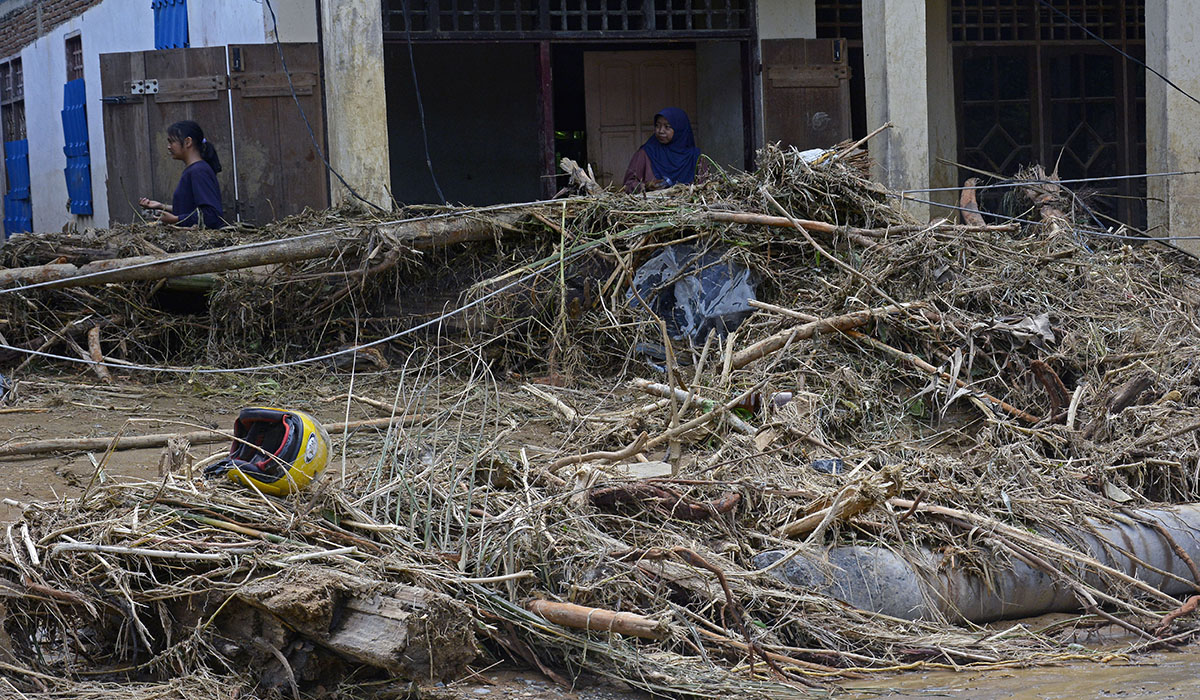 Warga melintas di depan rumah yang terdampak banjir bandang di Desa Kaili, Suli Barat, Kabupaten Luwu, Sulawesi Selatan, Minggu (5/5).