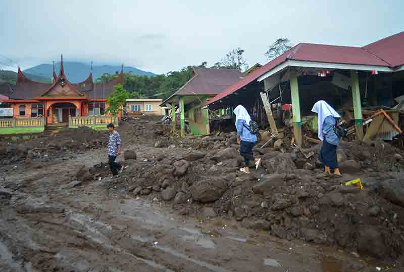 Pelajar melintas di depan sekolah yang hancur akibat banjir bandang di Jorong Galudua, Nagari Koto Tuo IV Koto, Agam, Sumatera Barat.