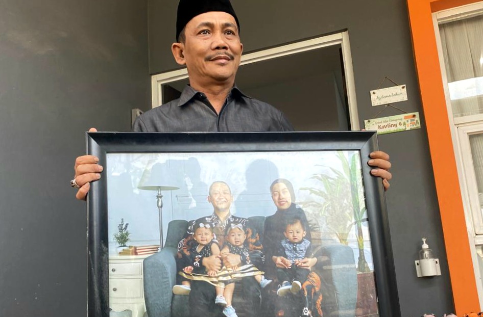 Kepala Desa Cihanjuang, Gagan Wirahma memperlihatkan foto korban Farid Ahmad bersama keluarganya. 