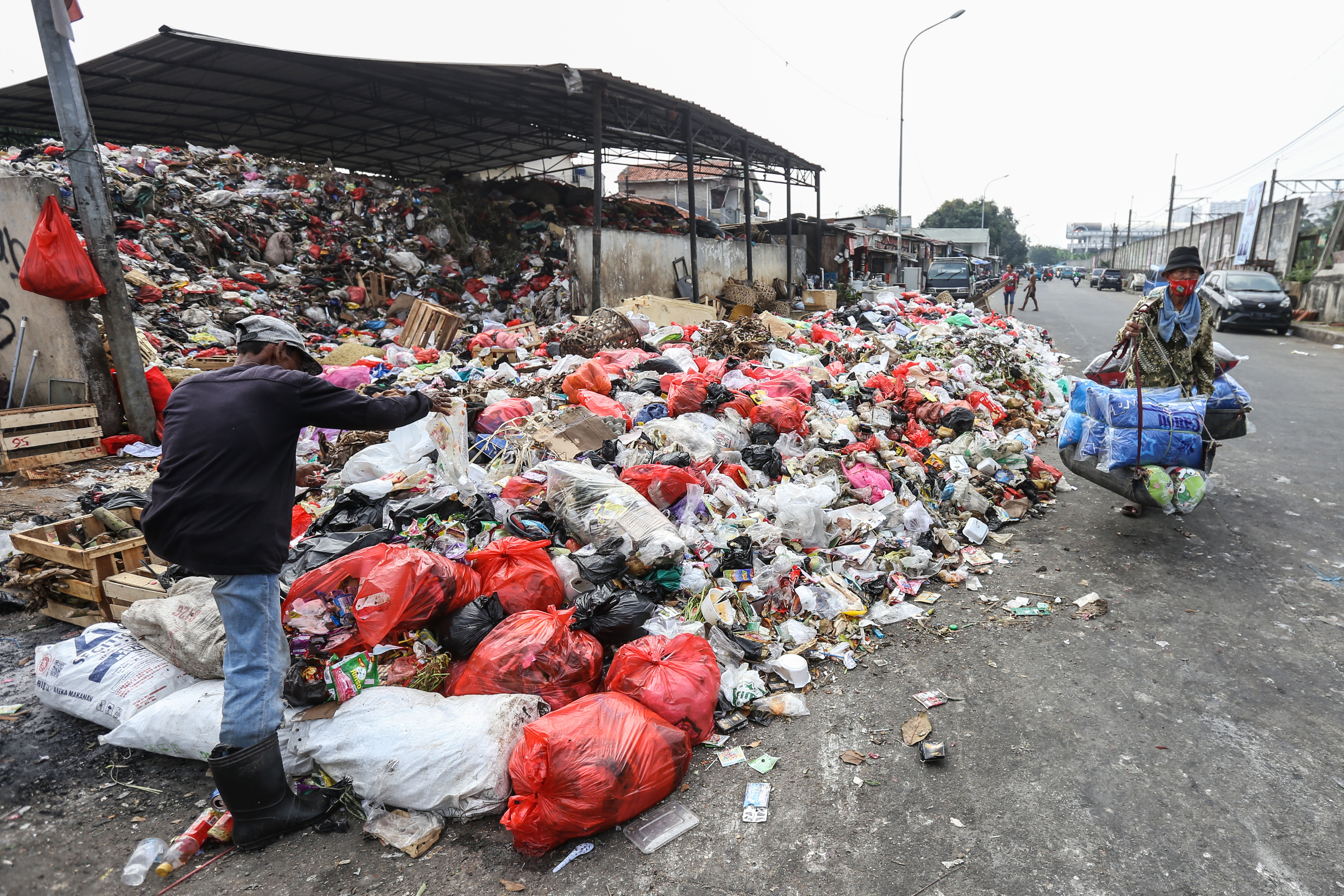Warga melintas di samping sampah yang meluber ke jalan 