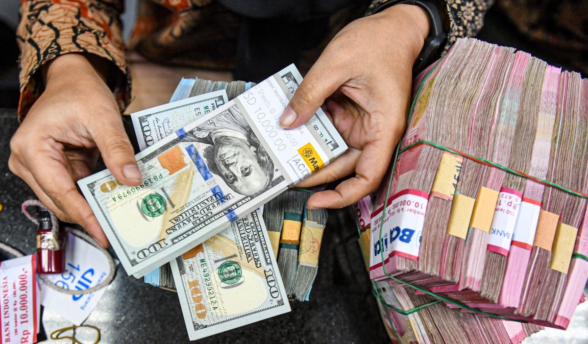 Petugas menyusun uang pecahan dolar AS dan rupiah di gerai penukaran mata uang asing VIP (Valuta Inti Prima) Money Changer, Jakarta.