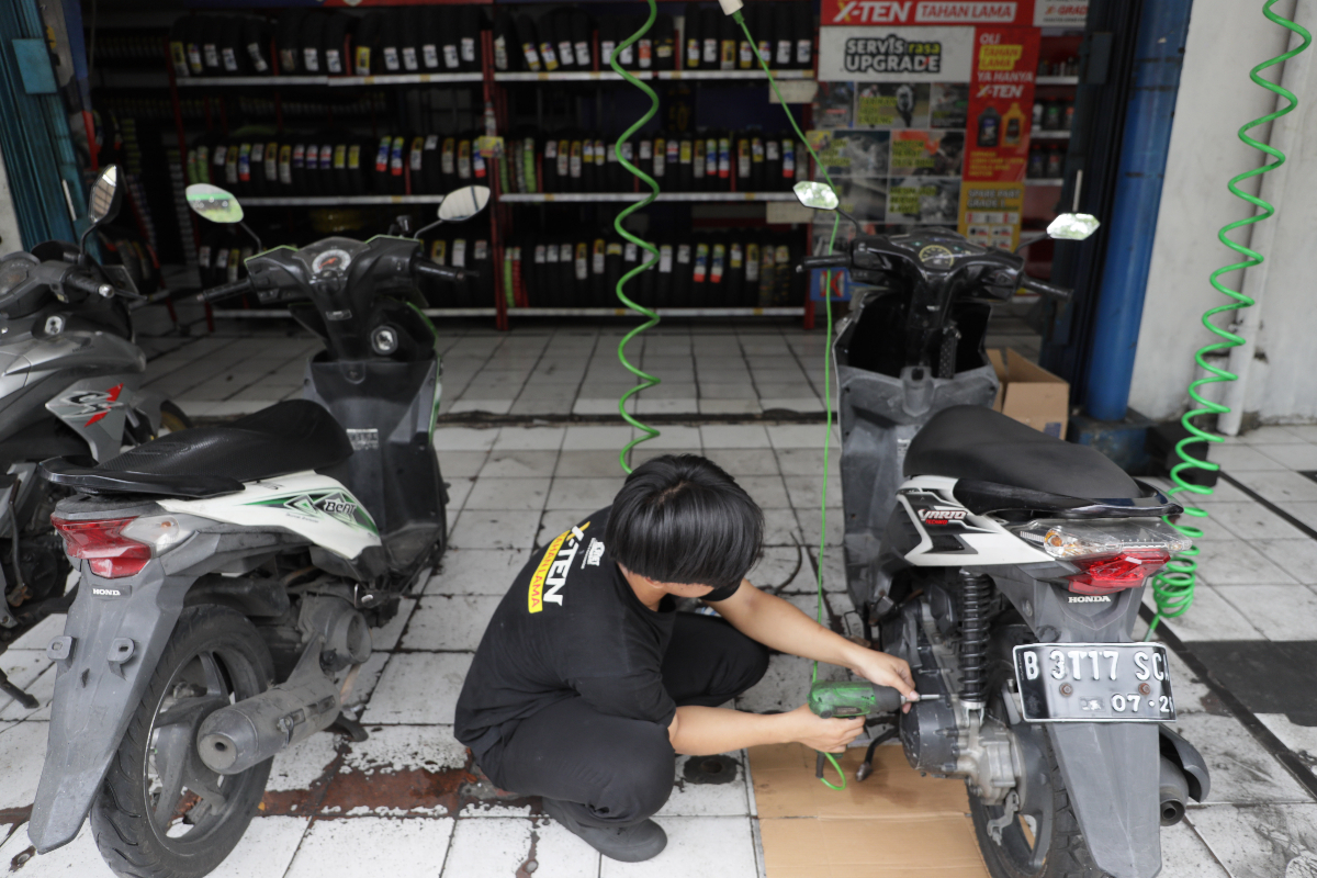 Montir melakukan perawatan motor di bengkel Planet Ban kawasan Kebun Jeruk, Jakarta.