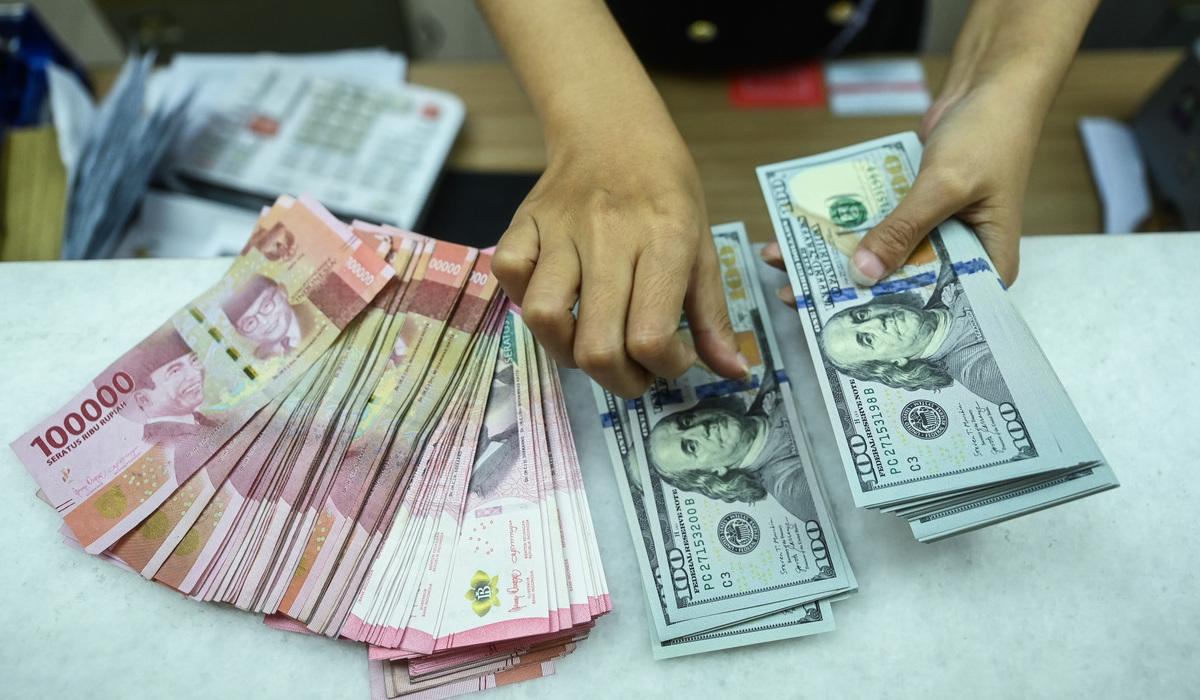 Petugas menghitung uang pecahan rupiah dan dolar AS.