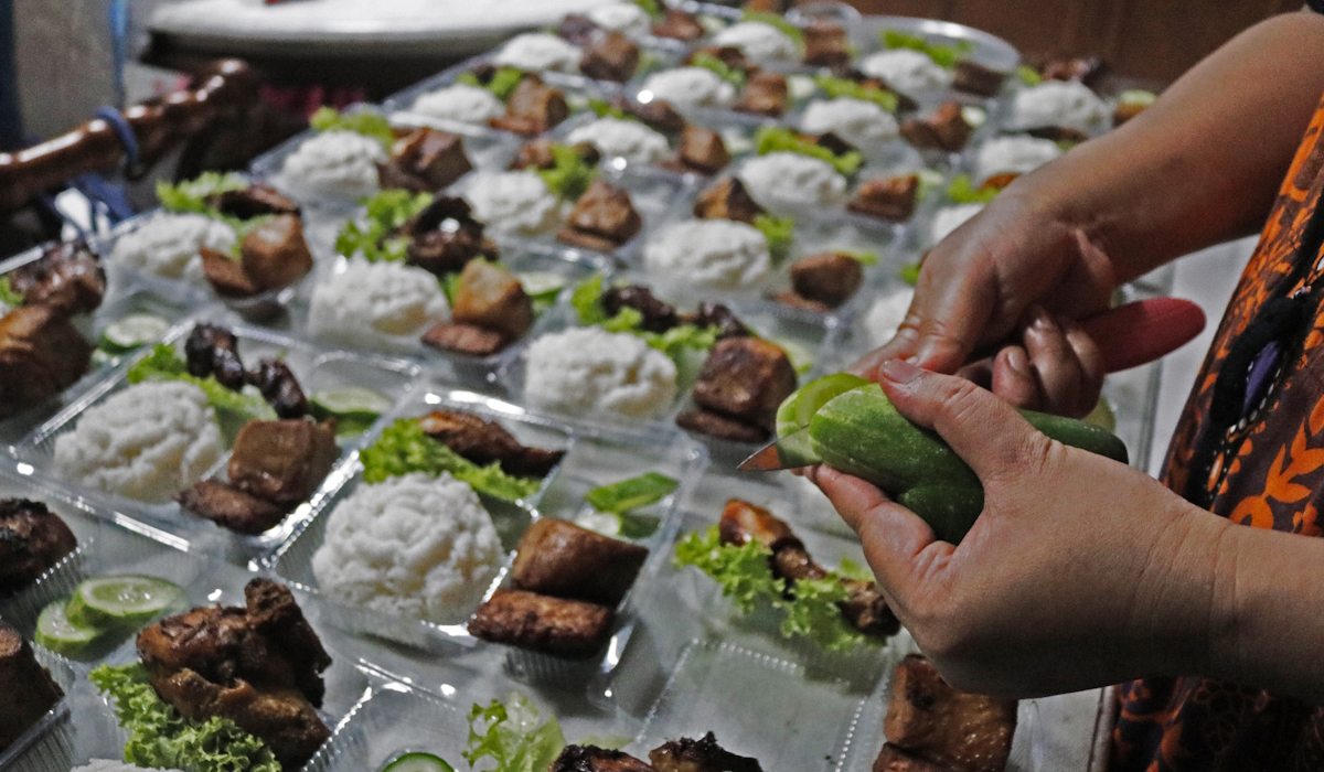 Ilustrasi seorang pekerja menyiapkan pesanan katering 