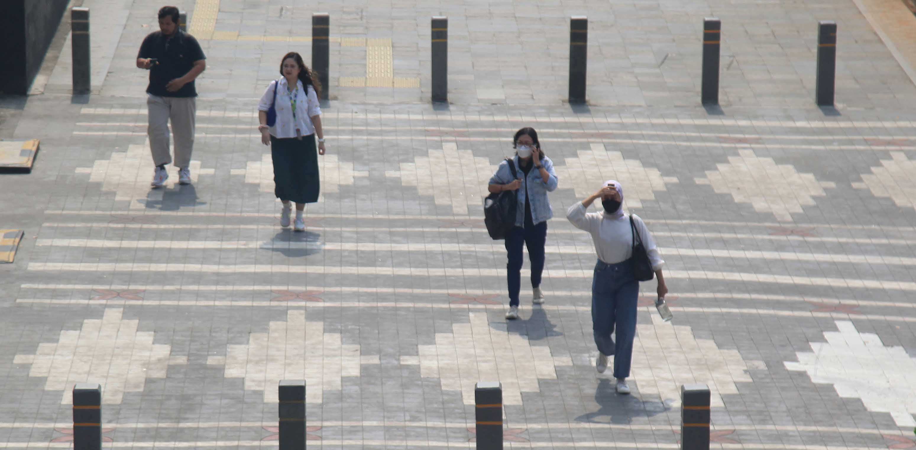 Warga melintas memakai masker untuk melindungi diri dari debu di JPO di Jalan Sudirman,Jakarta. 