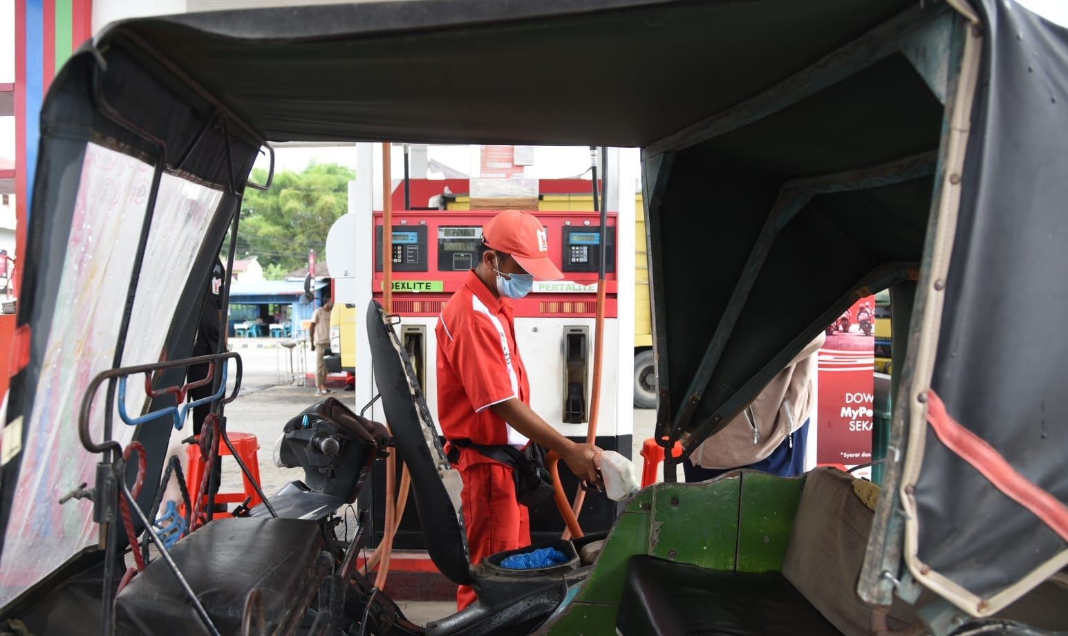 Petugas SPBU mengisi BBM bersubsidi ke sebuah becak bermotor. 