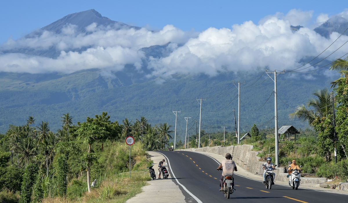 Pengendara sepeda motor melintas di jalan yang baru selesai ditingkatkan menuju kawasan wisata Gunung Rinjani di Senaru Lombok Utara