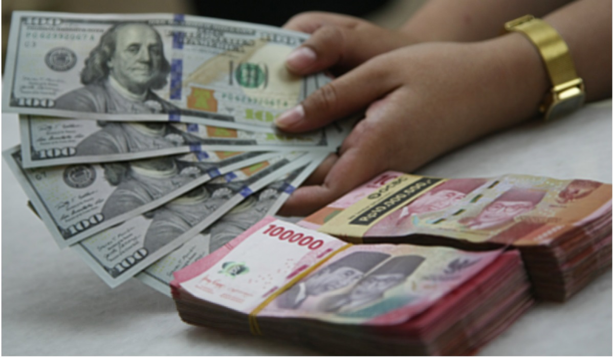 Petugas menunjukkan uang pecahan dolar AS dan rupiah di gerai penukaran mata uang asing di Jakarta, Selasa (18/6/2024).