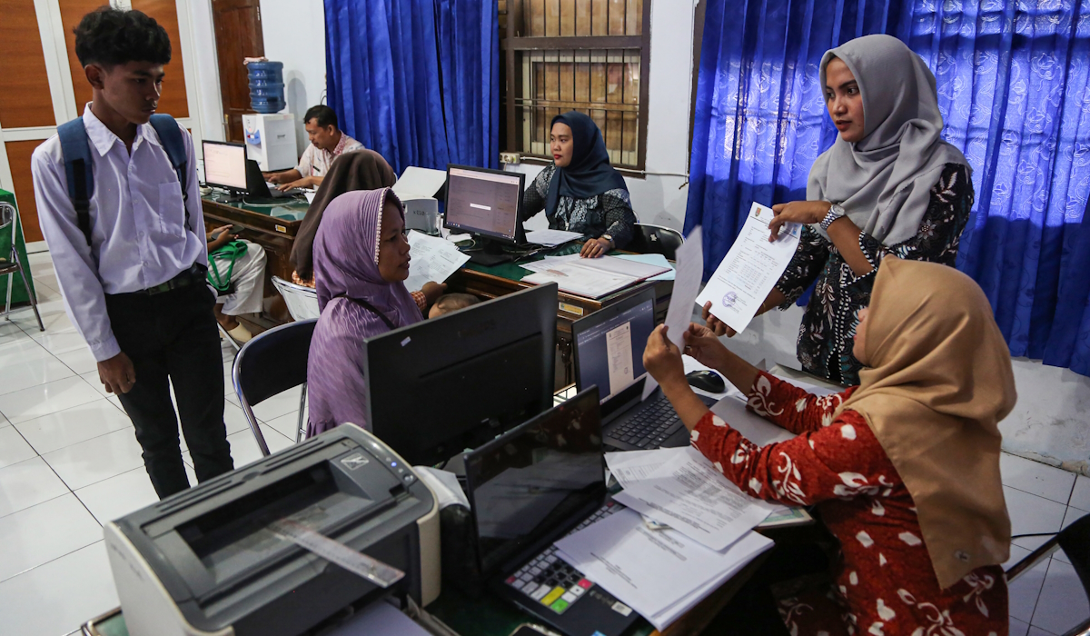 Petugas membantu orang tua murid calon peserta didik melakukan pengecekan kelengkapan berkas saat pendaftaran PPDB 