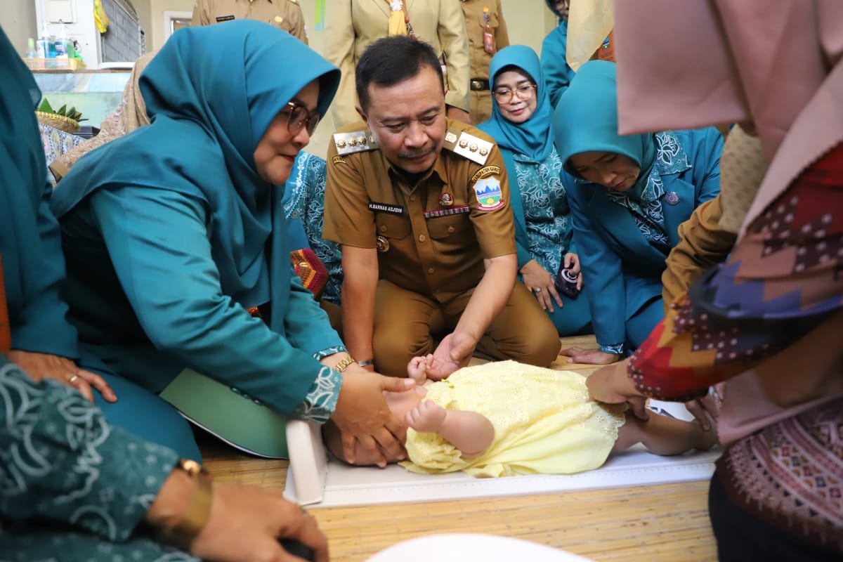 Penjabat Bupati Garut Barnas Adjidin memperhatikan proses penimbangan balita di posyandu. 