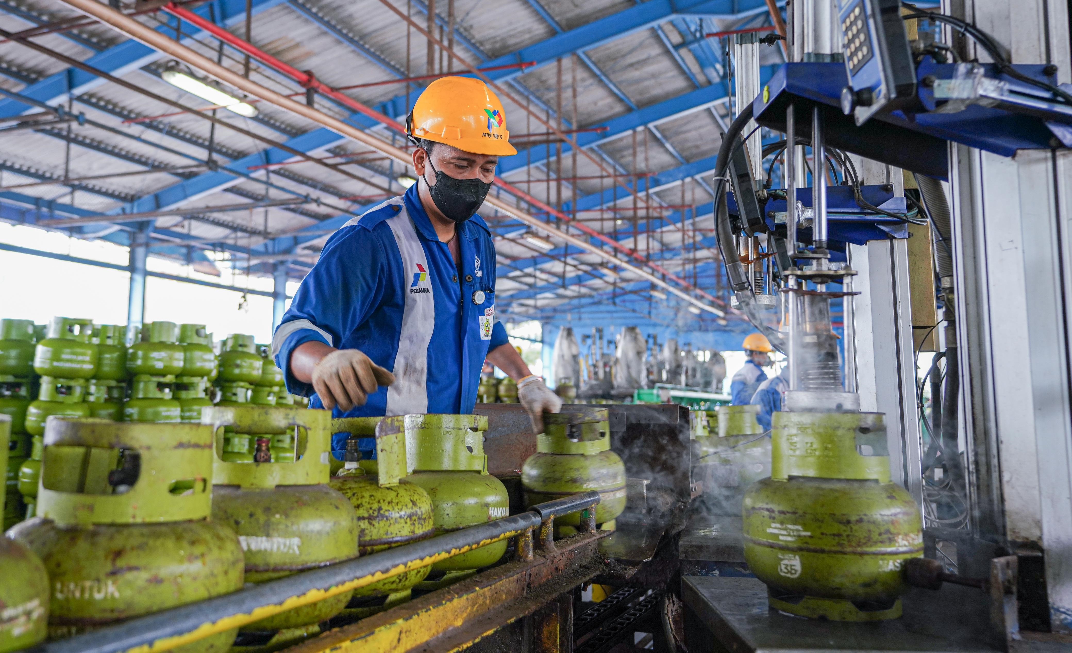 Petugas mengisi tabung gas ukuran 3 kg. 