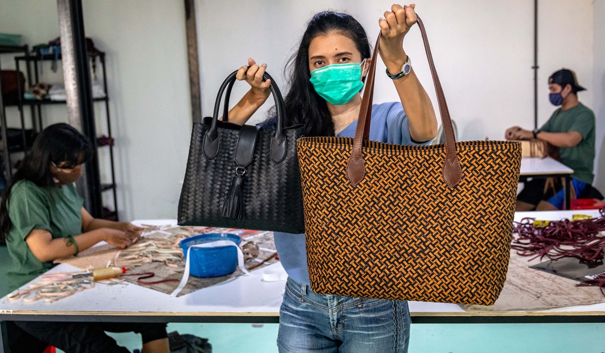 Ilustrasi--Seorang pengusaha memperlihatkan tas anyaman kulit produknya.