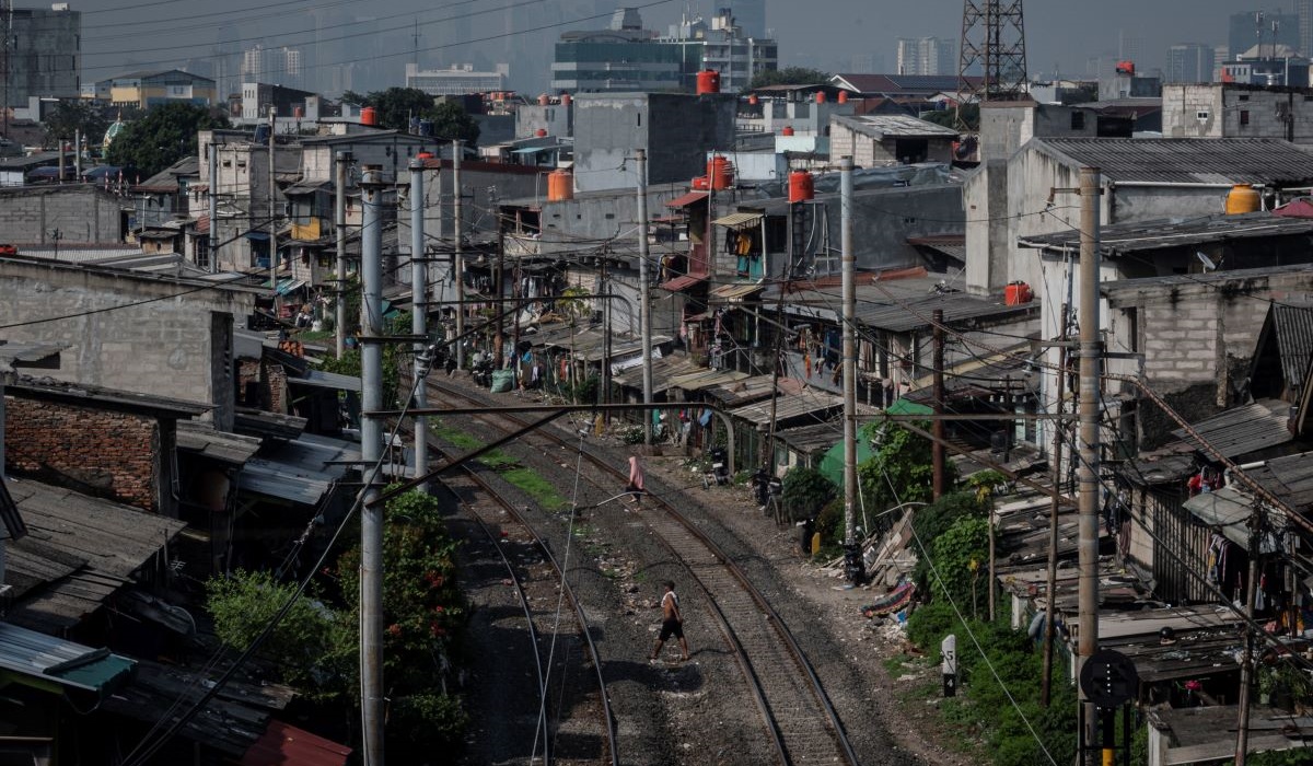 Warga menyeberangi perlintasan kereta api di kawasan permukiman padat penduduk di Cideng, Jakarta, Rabu (19/6/2024).
