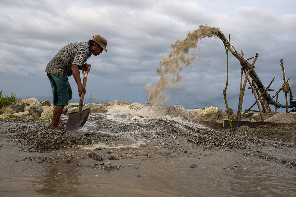 Penambang tradisional menyekop pasir yang keluar dari selang penyedot di kawasan pertambangan pasir rakyat, Desa Sunju, Sigi, Sulteng.