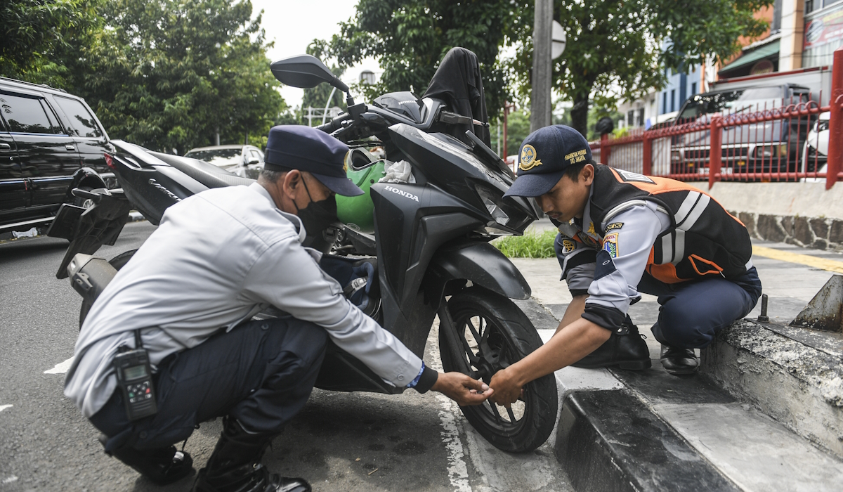 Petugas Suku Dinas Perhubungan Jakarta Barat mencabut pentil sepeda motor yang diparkir di bahu jalan di kawasan Kembangan 