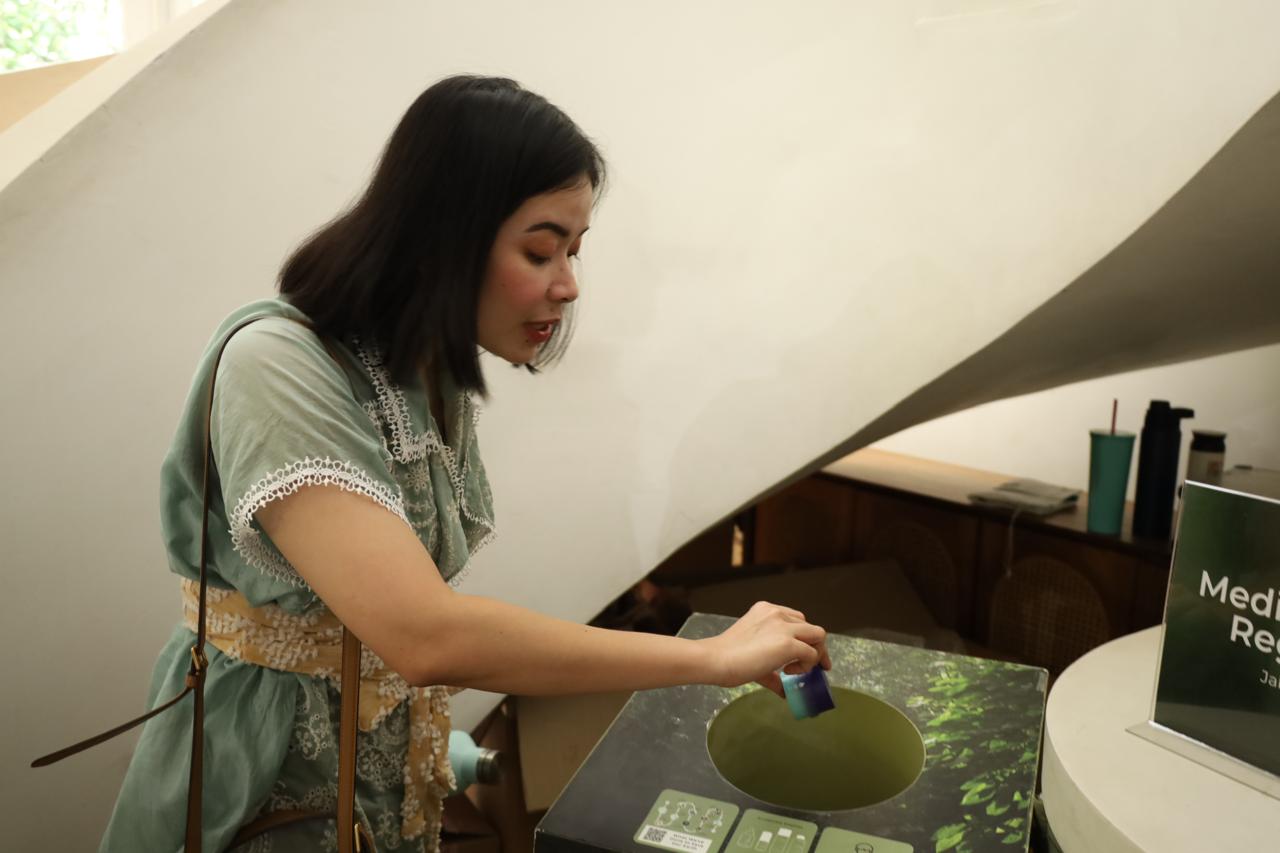 Seorang perempuan membuang sampah kemasan skincare pada drop box Avoskin untuk didaur ulang. 