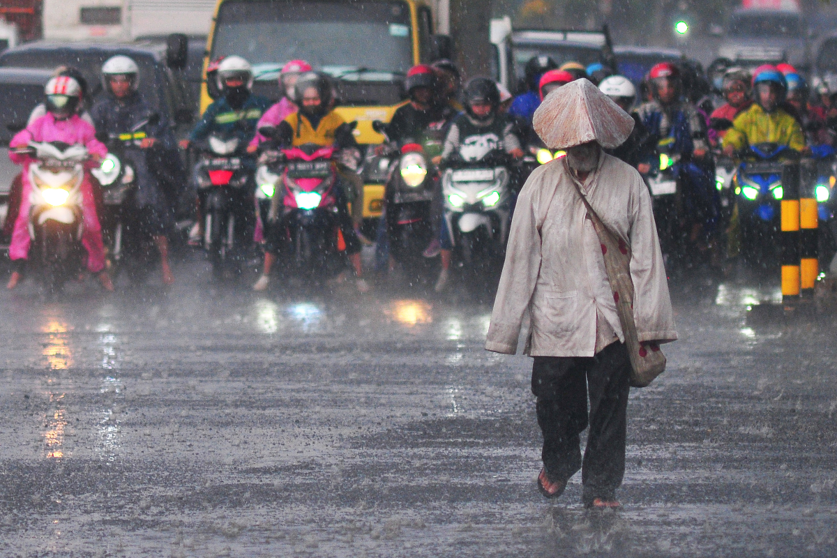 Seorang pejalan kaki melintas saat hujan di jalan Agil Kusumadya, Kudus, Jawa Tengah