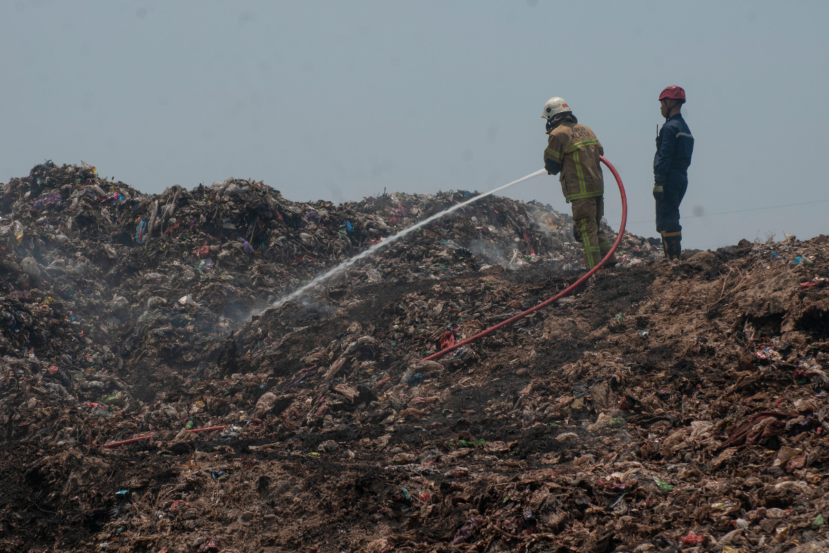 Petugas pemadam kebakaran menyemprotkan air saat proses pendinginan pada kebakaran tumpukan sampah di TPA