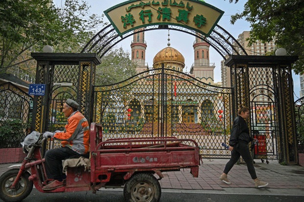 Seorang warga muslim Uighur melintasi Masjid Noghay di Provinsi Xinjiang, Tiongkok.