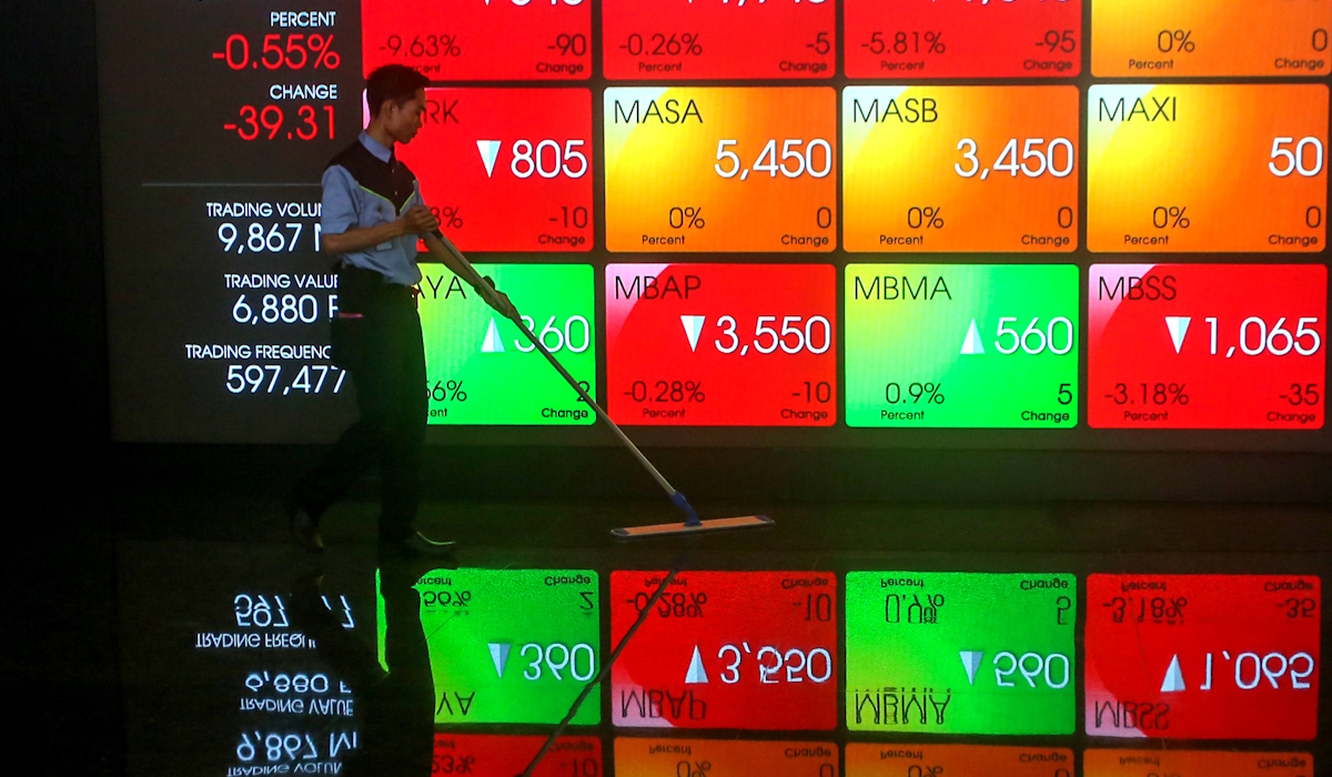 Pekerja melakukan aktivitas dengan latar belakang layar yang menampilkan pergerakan IHSG