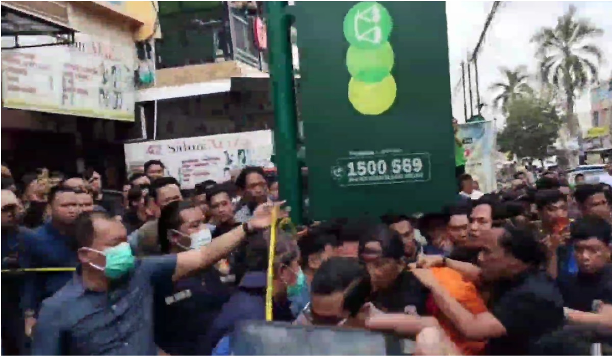 Tersangka memakai baju oranye dibawa polisi.