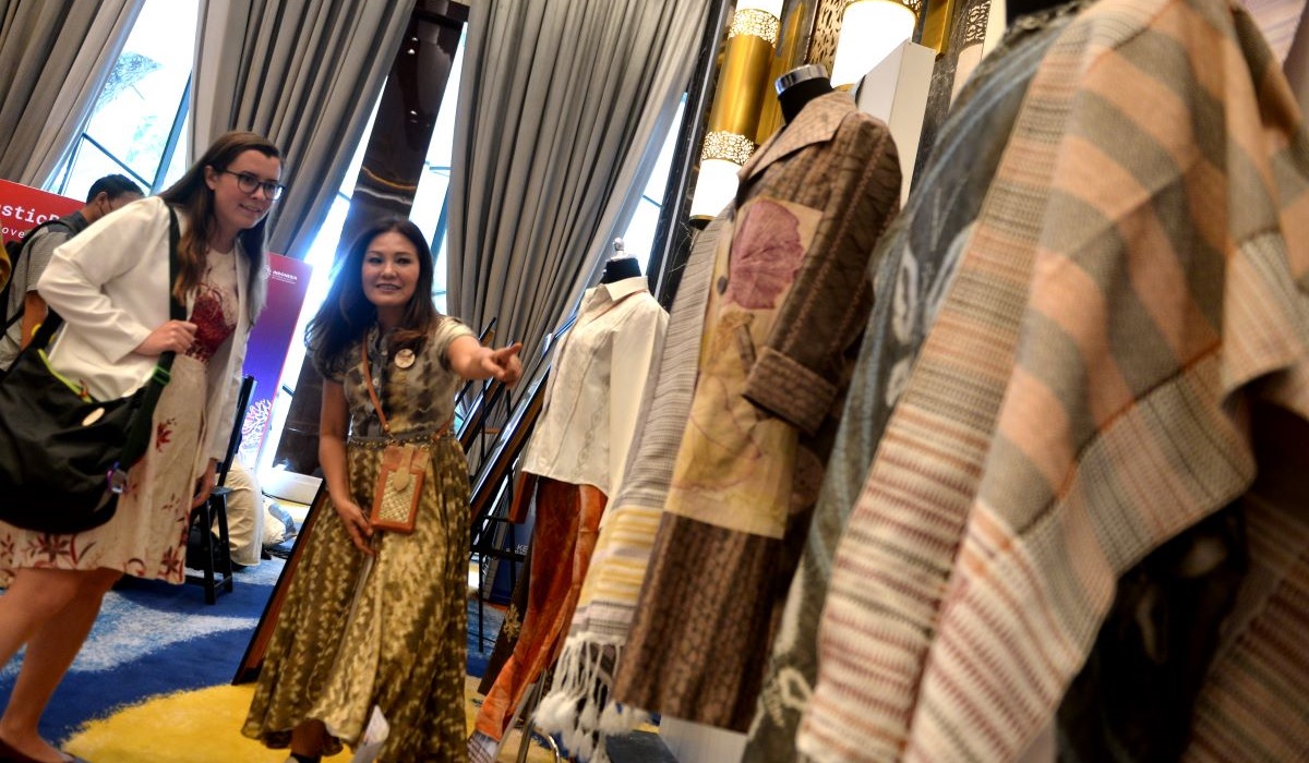 Pengunjung mengamati pakaian yang diproduksi menggunakan bahan benang dari sampah plastik.