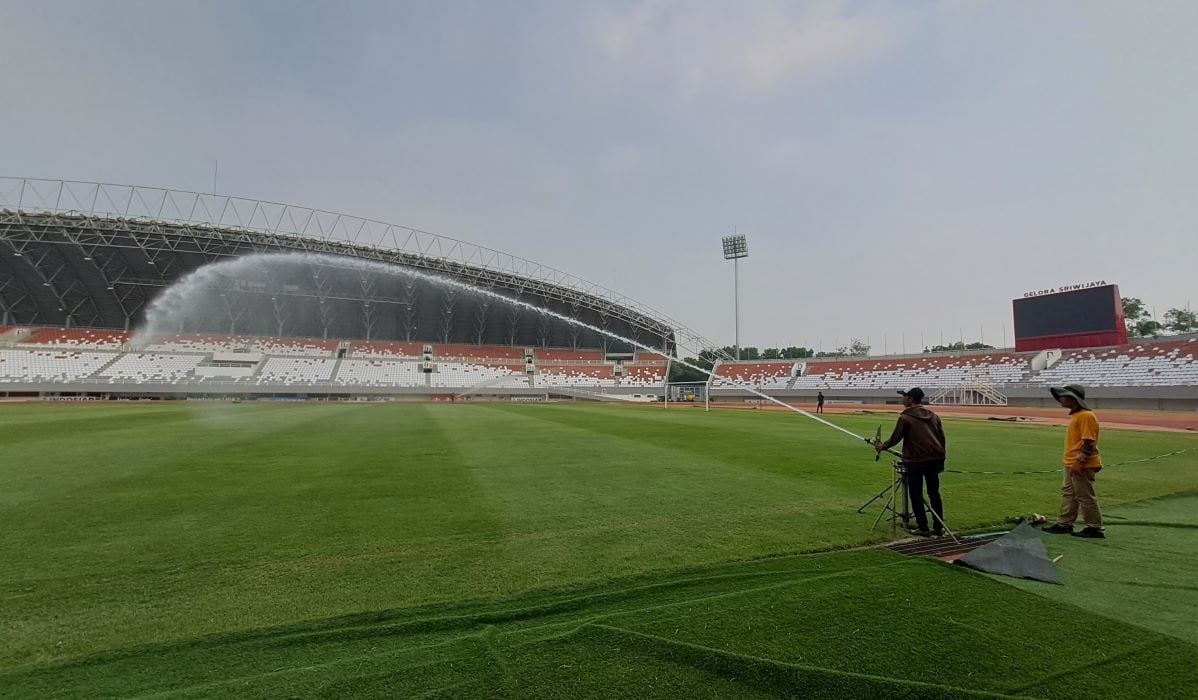 Petugas sedang melakukan pembasahan rumput di lapangan sepak bola Stadion Gelora Sriwijaya Jakabaring Palembang, Minggu (15/10/2023).