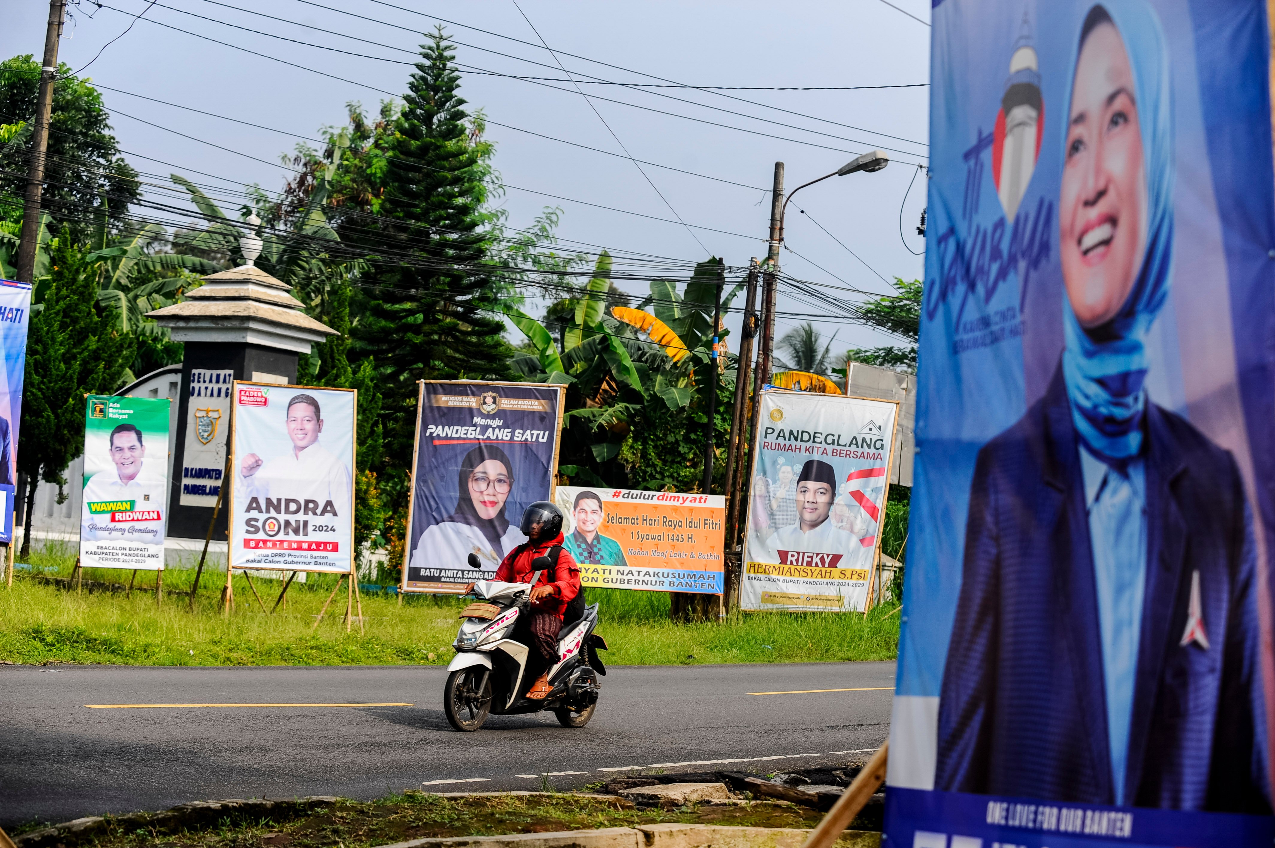 Pengendara roda dua melintas di depan alat peraga kampanye (APK) di Pandeglang, Banten