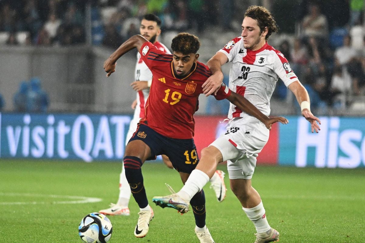 Penyerang muda Spanyol Lamine Yamal sedang mempertahankan bola dari pemain lawan.