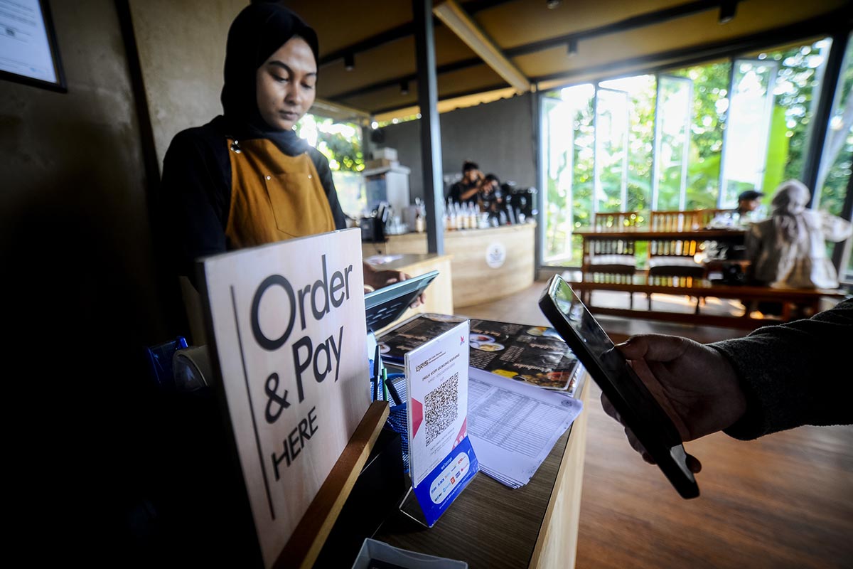 Konsumen memindai kode batang pembayaran digital Quick Response Indonesia Standard (QRIS) di sebuah coffee shop.