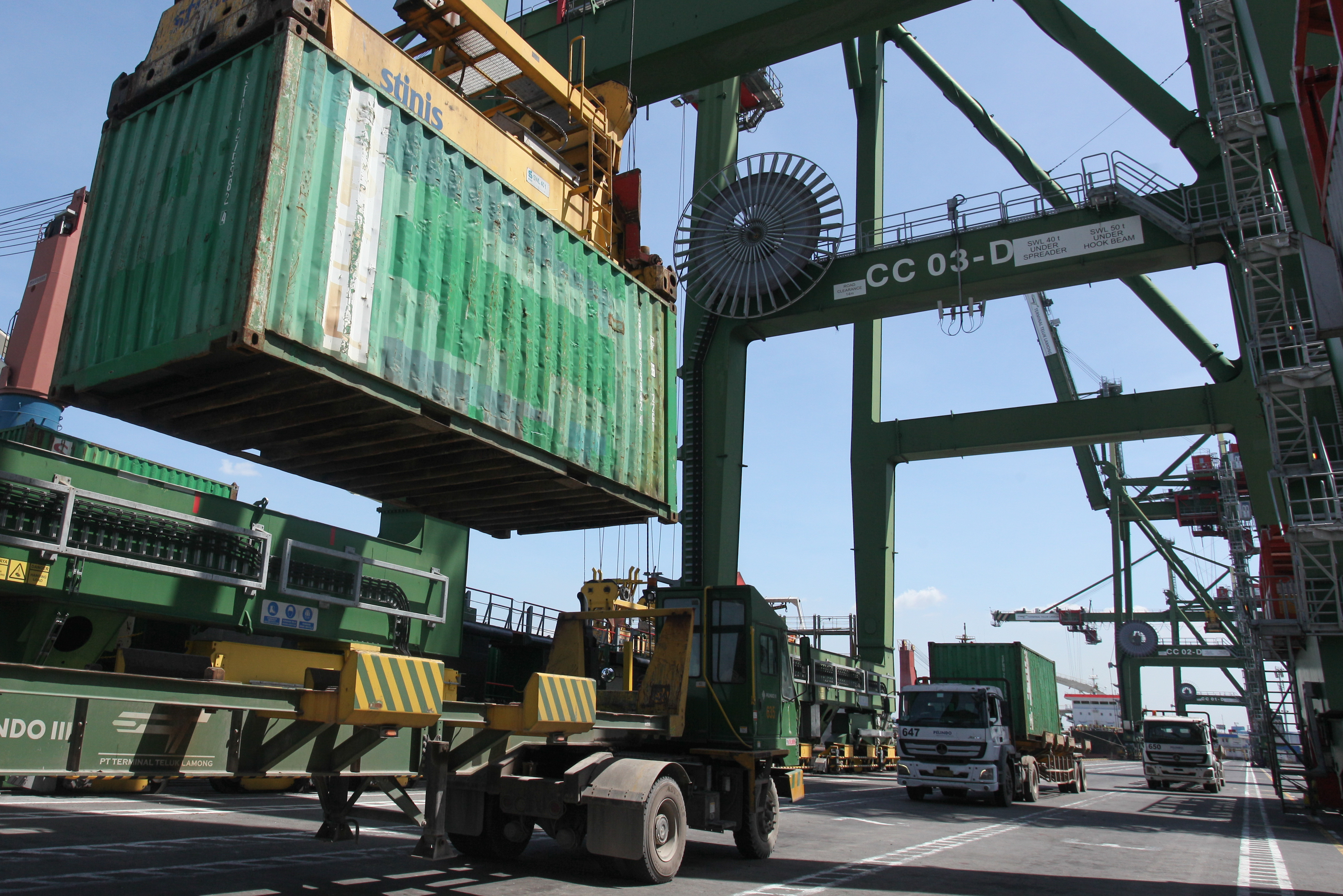 Operator crane memindahkan peti kemas dari mapal kargo ke truk di Terminal Teluk Lamong, Surabaya