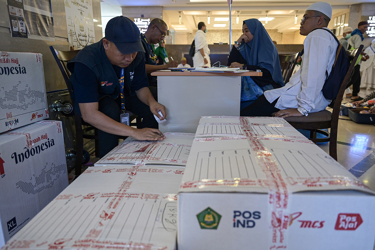 Petugas PT Pos Indonesia (Persero) memasang label pada paket yang akan dikirim jamaah haji Indonesia.