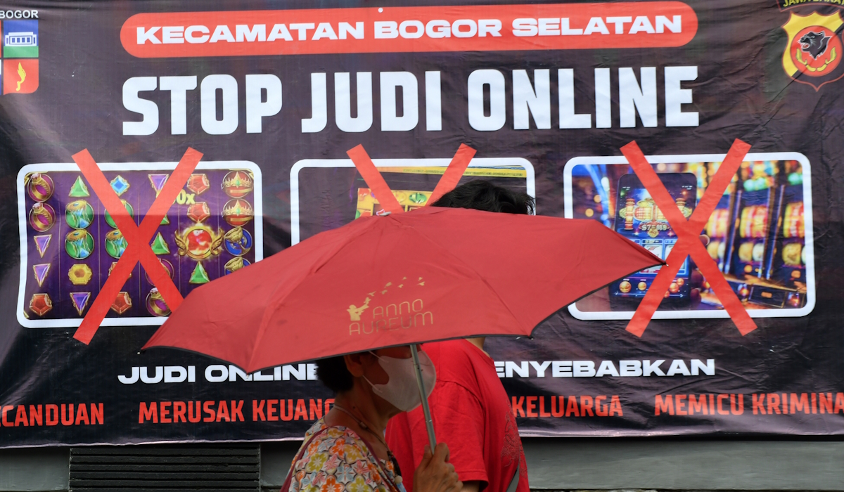 Warga berjalan di depan spanduk sosialisasi larangan judi online di Kantor Kecamatan Bogor Selatan 