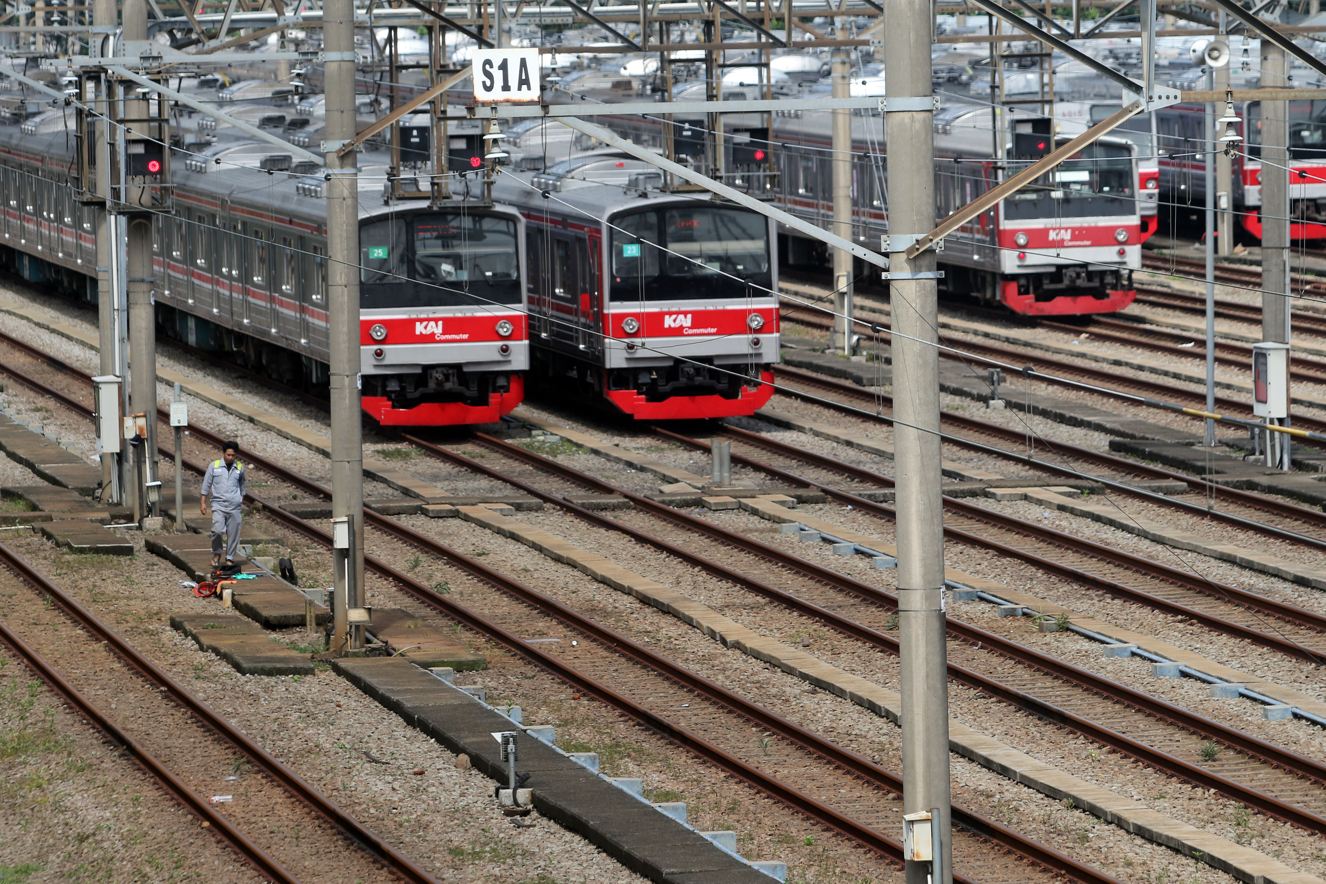 Petugas berjalan di dekat sejumlah rangkaian kereta rel listrik (KRL) di Dipo KRL Depok, Jawa Barat, Jumat (5/7).