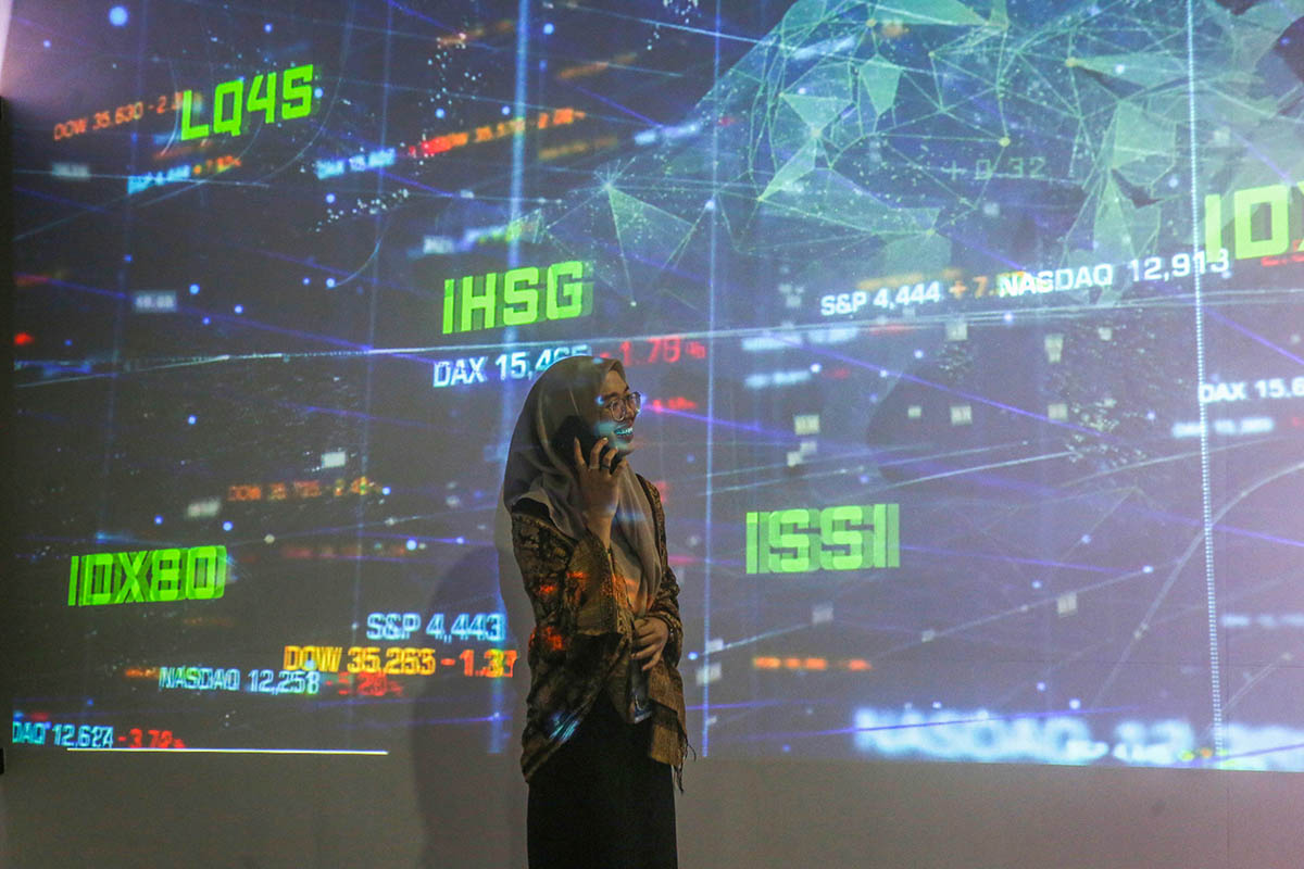 Seorang pialang melakukan aktivitas dengan latar belakang layar yang menampilkan pergerakan Indeks Harga Saham Gabungan (IHSG).