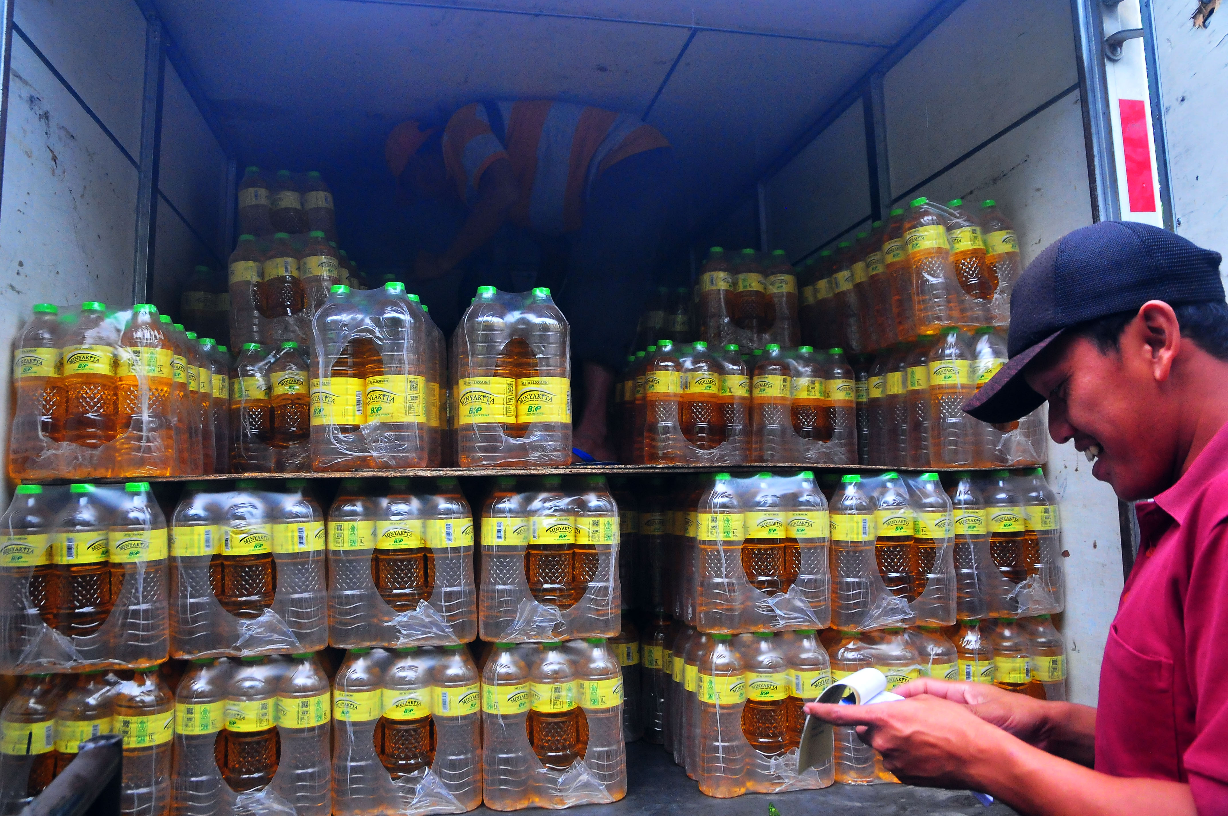 Pekerja bersiap memindahkan minyak goreng MinyaKita dari mobil saat pendistribusian.