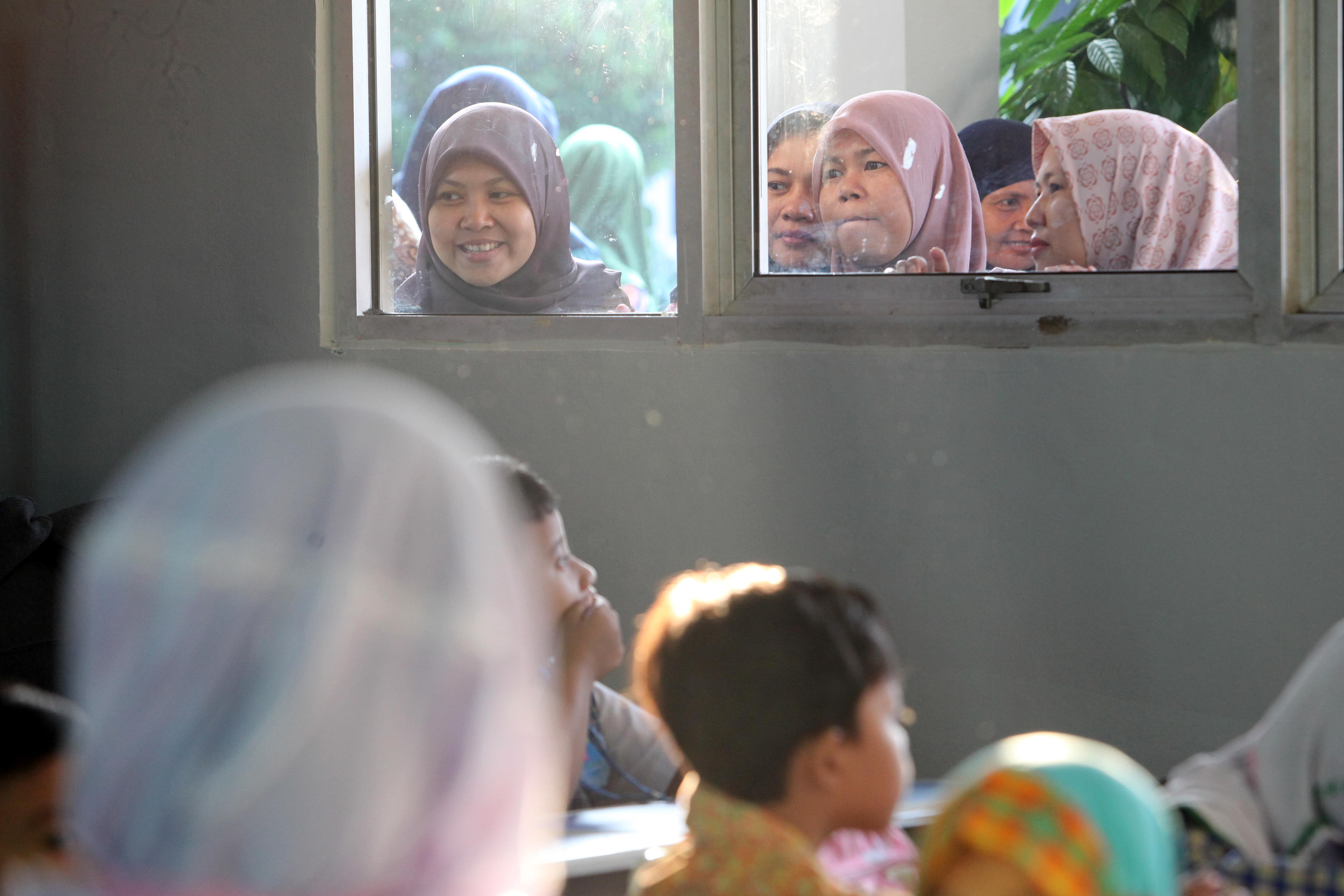 Orangtua memantau anak-anaknya dari jendela saat pertama kali bersekolah