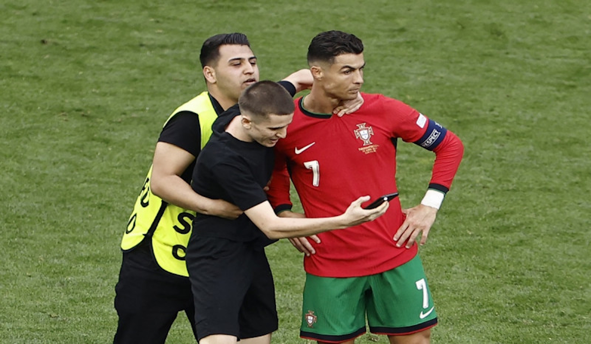 Seorang penonton yang menerobos melakukan swafoto dengan bintang timnas Portugal Cristiano Ronaldo di laga Euro 2024.