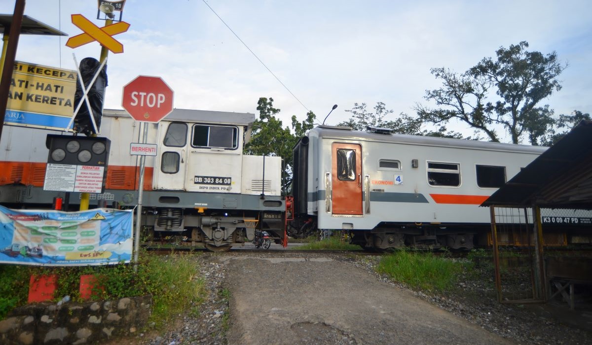 Kereta api melintas di perlintasan tanpa palang pintu yang memiliki Early Warning System tetapi tidak berfungsi di Muaro Kasang, Padang.