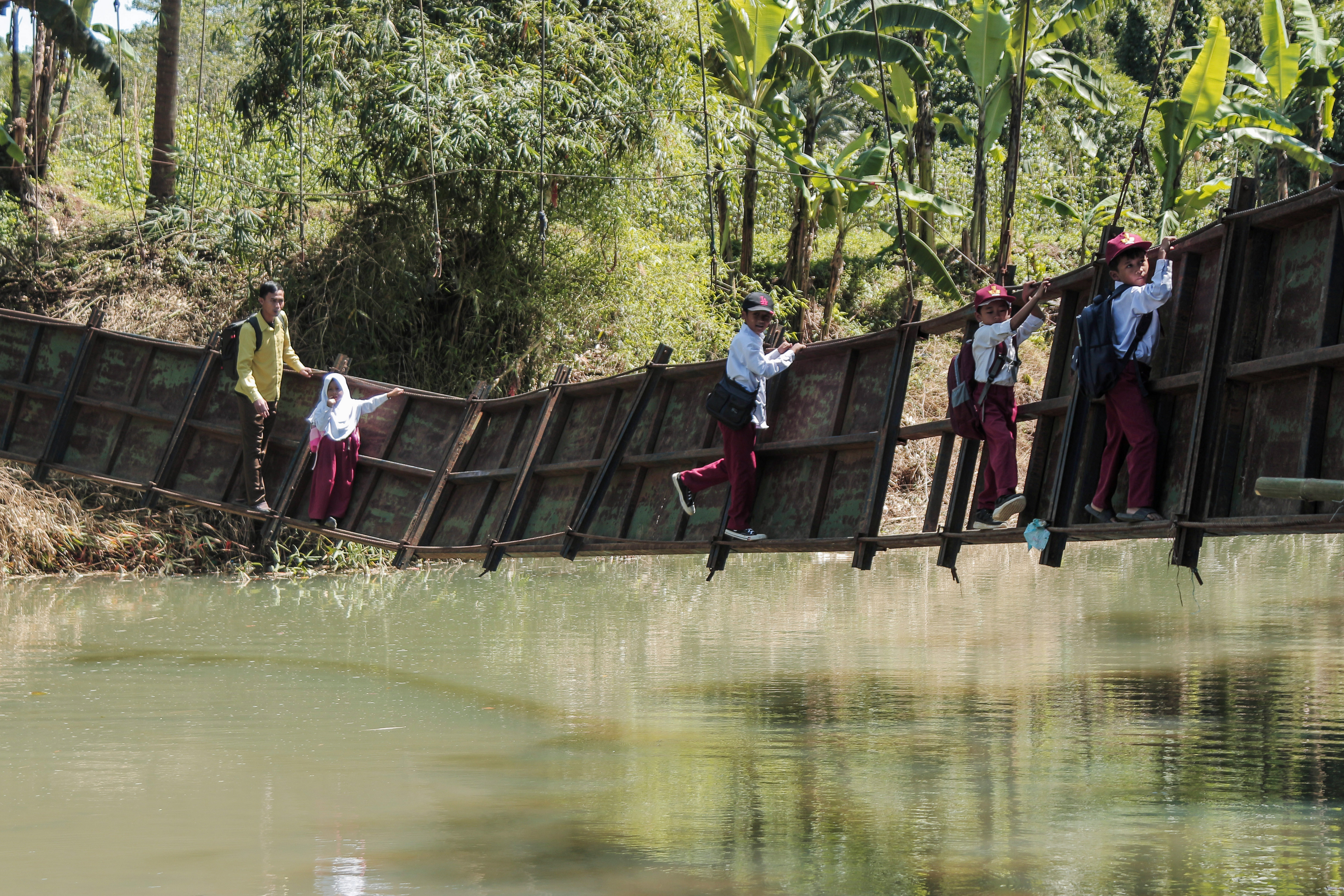 Siswa berusaha melintasi jembatan rusak di Neglasari, Lengkong, Sukabumi, Jawa Barat, Selasa (23/7).