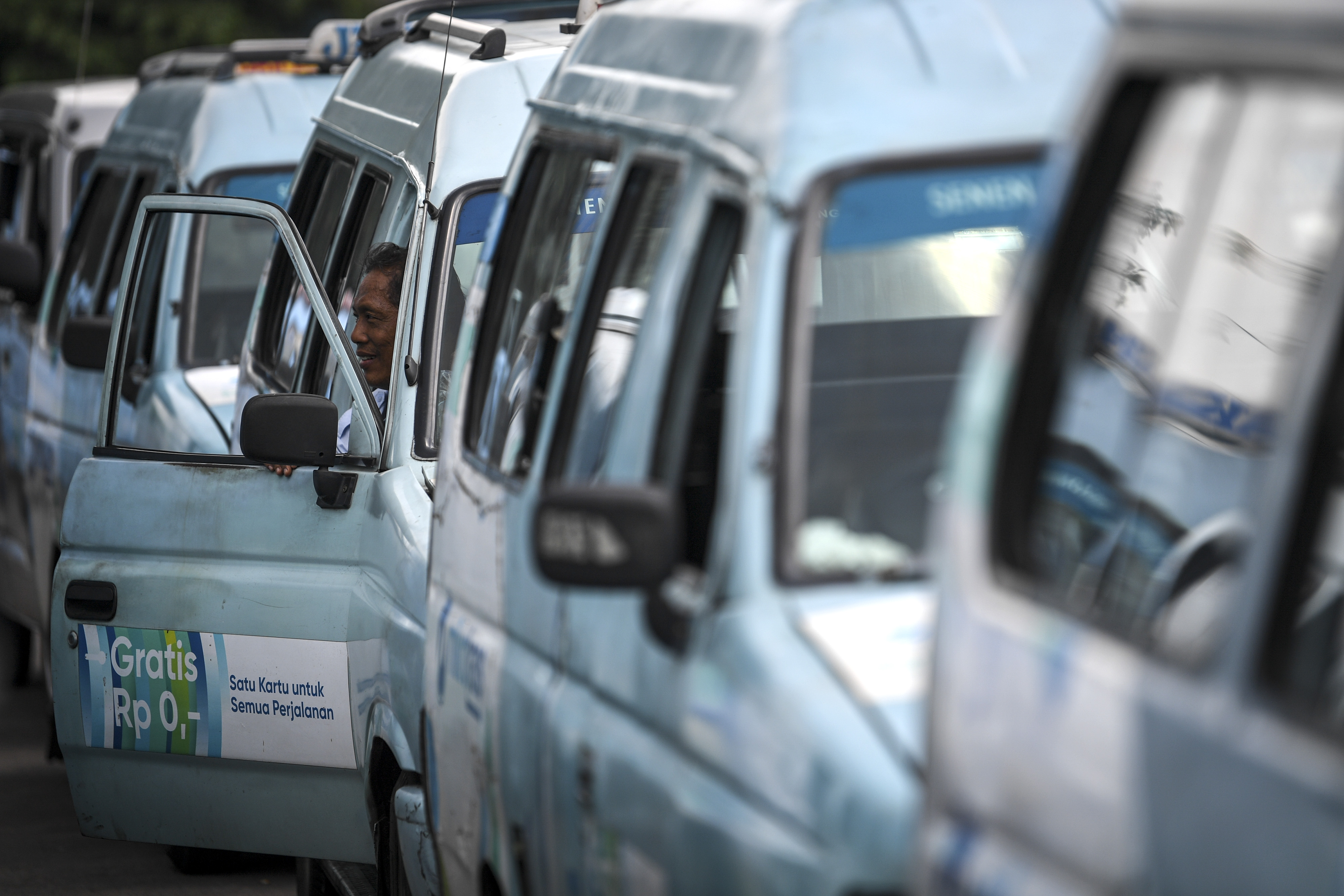 Seorang sopir angkutan kota Mikrotrans berada di dalam armadanya di Terminal Pulo Gadung, Jakarta. 
